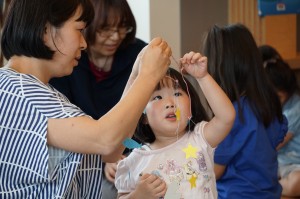 作りかけのモビールを見つめる子どもと見守る母親の写真