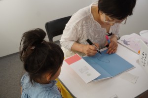 本の裏表紙にサインを描くうつみのりこさんの写真