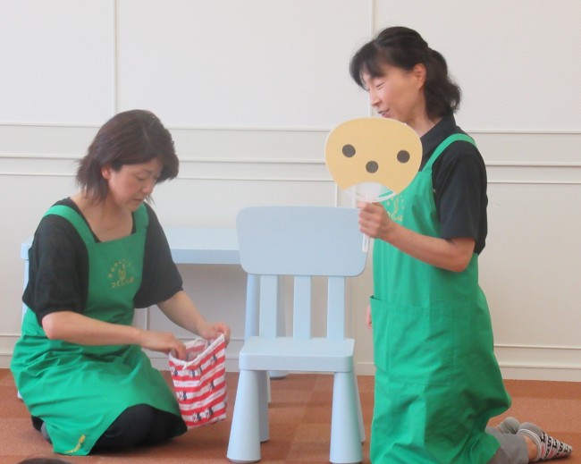 黒い丸が3点描かれたうちわを持つスタッフの写真