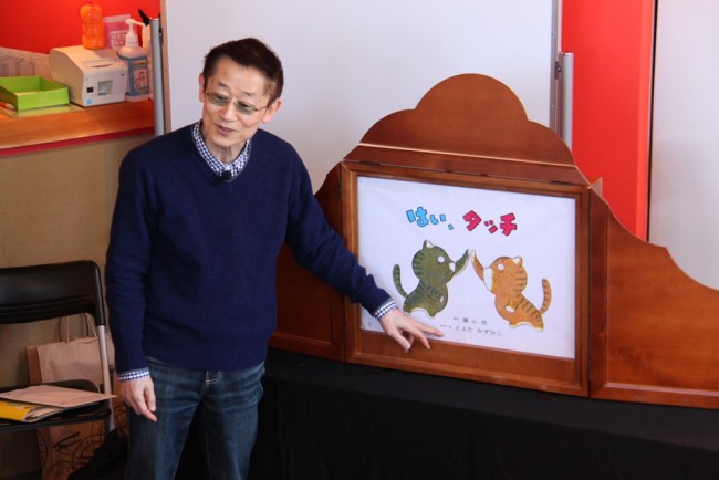 紙芝居を指さすとよたかずひこさんの写真
