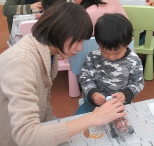 ペットボトルの、トナカイの花となる部分に青い紙を貼る子どもの写真