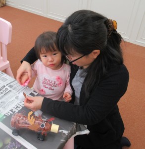 手取り足取りでトナカイペットボトルを作る子どもの写真