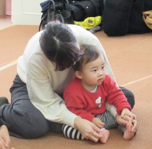 後ろからお母さんに抱きかかえられている子どもの写真