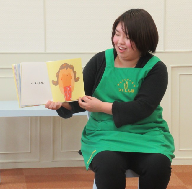 絵本を開いて読み聞かせをしている女性の写真