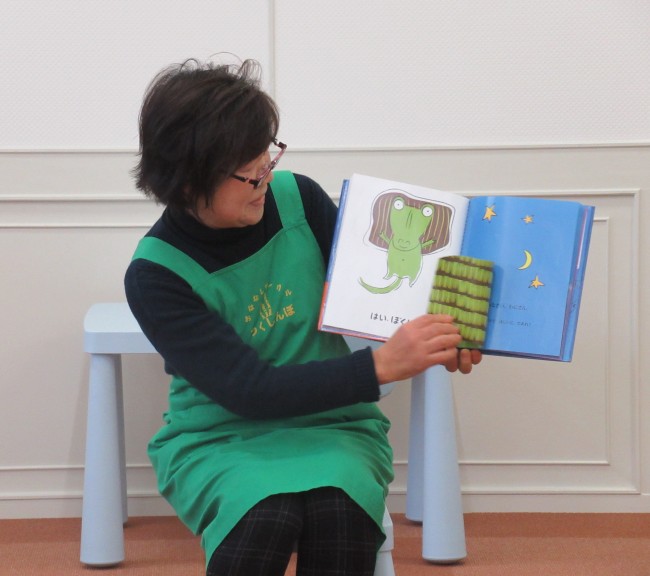 わにくんの絵本と布を見せて読み聞かせをする女性の写真