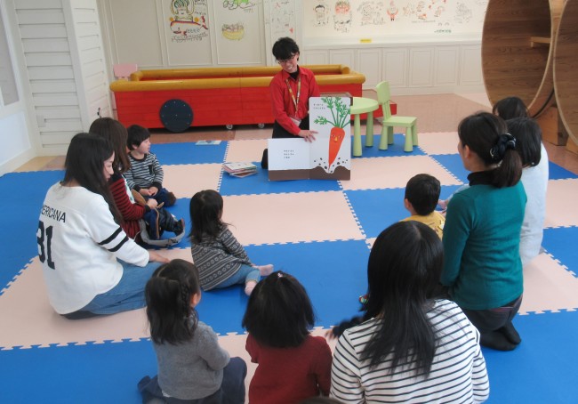 絵本を紹介する先生とそれを聞く子どもたちの写真