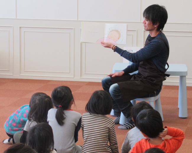 赤ちゃんの描いてあるページを見せて読み聞かせをするスタッフの写真
