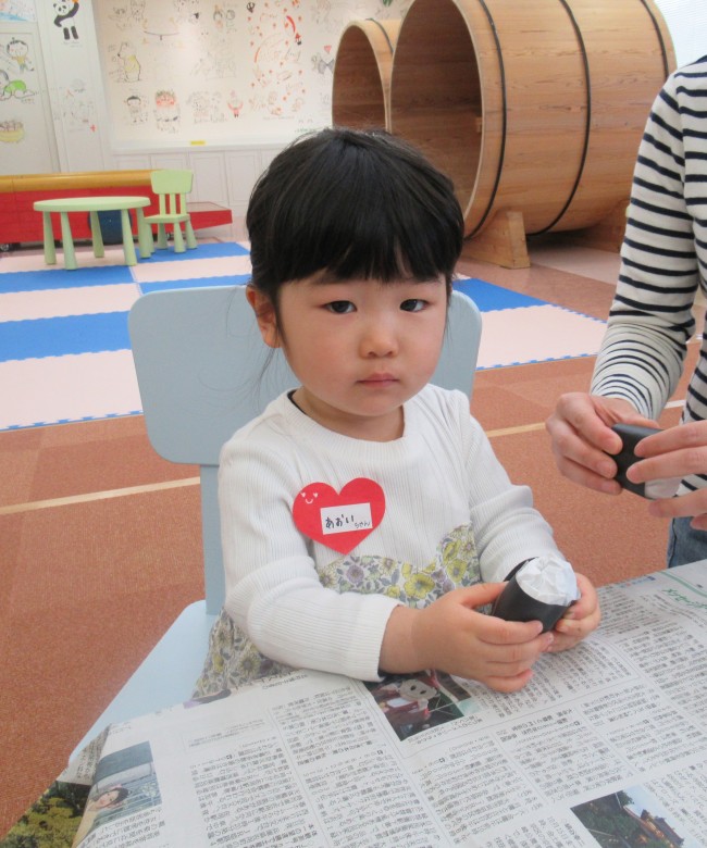 紙で作られたのり巻きを持つ子どもの写真