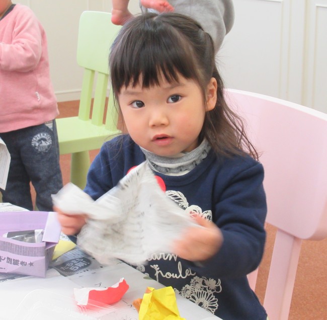 新聞紙を丸めようとする子どもの写真