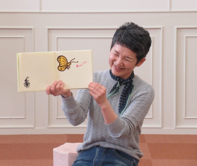 ちょうちょとアリと「おーい」というセリフが描かれた絵本を持つスタッフの写真