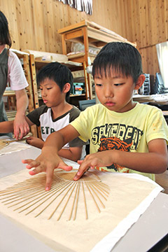 男の子がうちわ作りを体験している様子