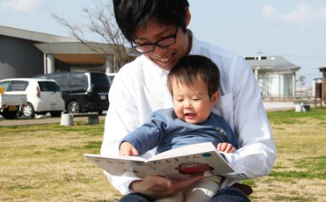 息子と一緒にお父さんが絵本を読んでいる写真