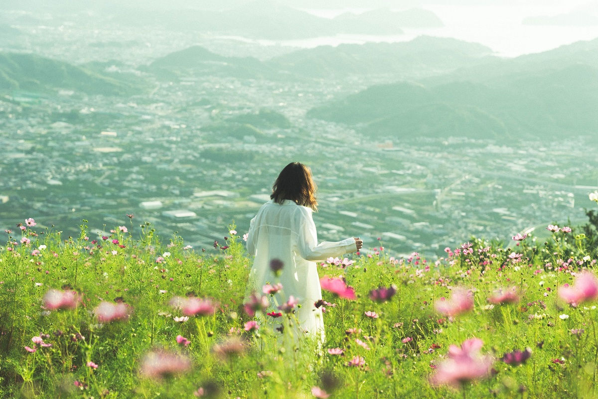 鷲ヶ峰コスモスパークから手前にコスモス・女性・奥に有田川町と有田市の景色が写った写真