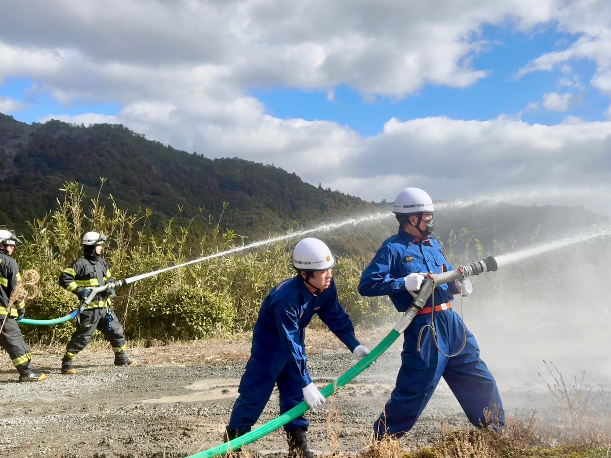 消防団員と消防署員が放水を実施しています。