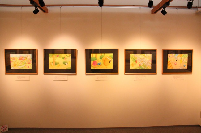 展示の様子で、壁に掛けられた数枚の絵の写真