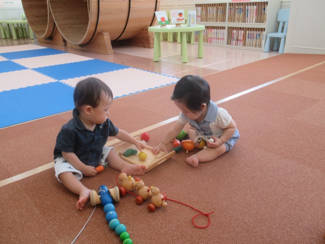 木のおもちゃで一緒に遊ぶ二人の子どもの写真