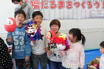 できあがった福だるまを持ってポーズをとる子どもたちと青山先生の写真
