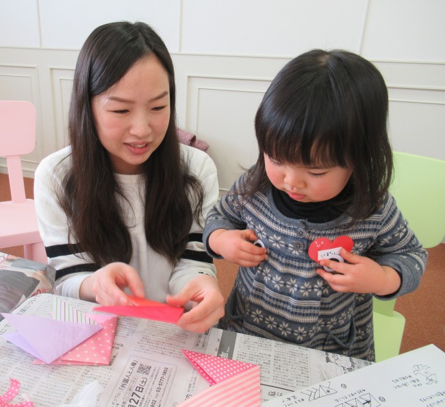 折り紙でおさかなを作る子供の写真