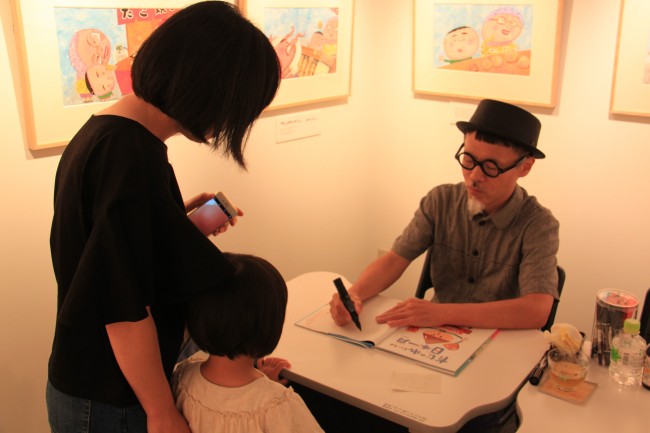 絵本にサインをする長谷川先生の写真