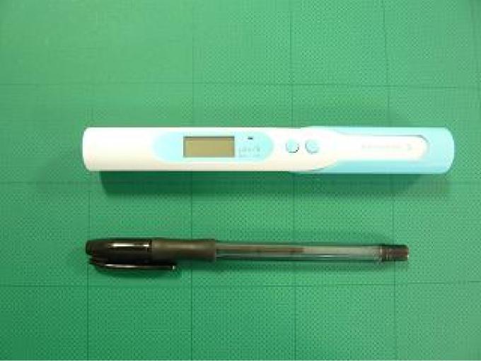 家庭用放射線測定器とボールペンの大きさを比較する写真